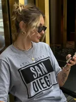 T-shirt feminina 100% Algodão Estampa San Diego, estampa basica em todas as variações, estampa branca na peça: vermelho, esmeralda, esmeralda e laranja, estampa preta na peça: areia, cinza, mescla e branca, é a peça perfeita para usar com jeans, alfaiataria, saias e composições de tendênciaciacia.